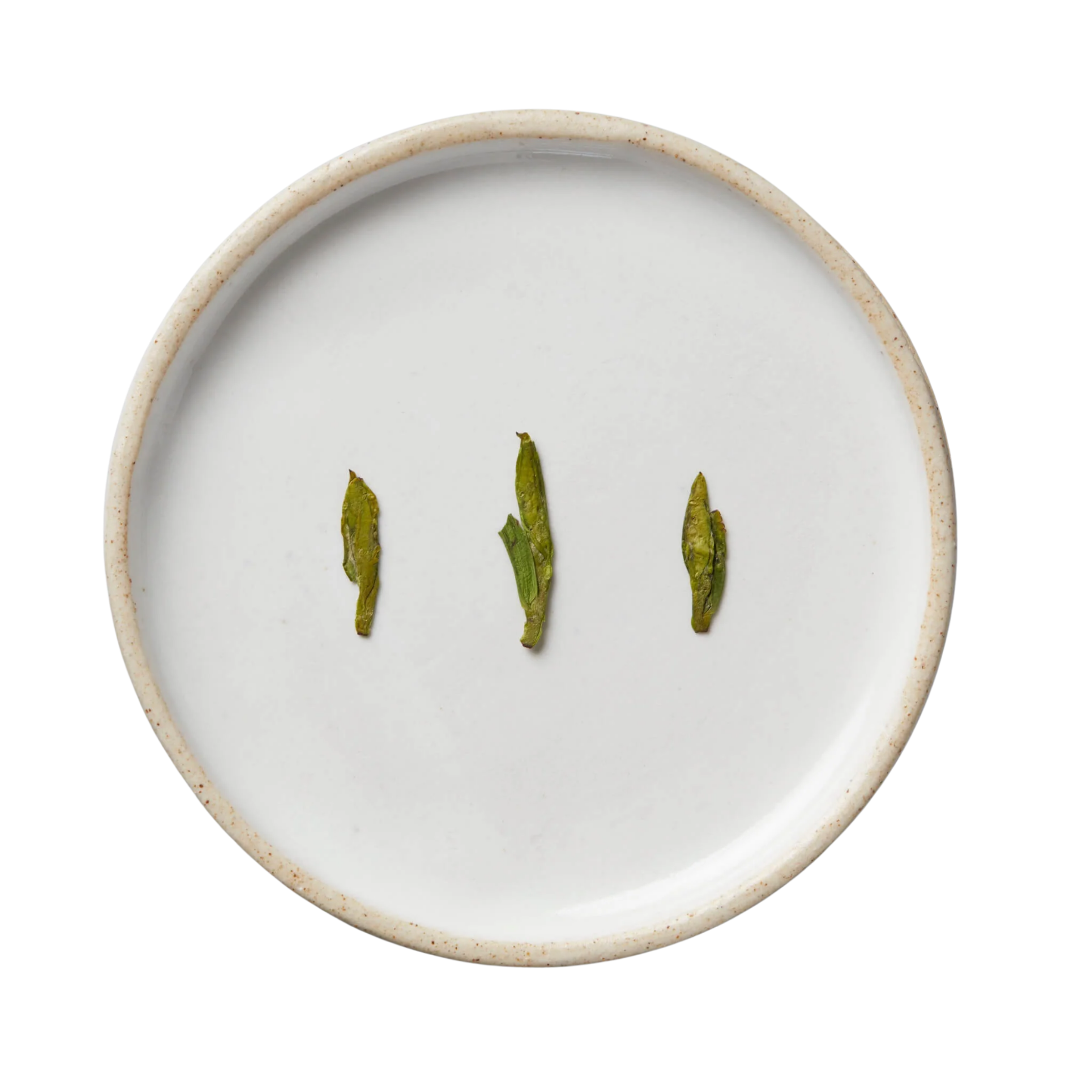 Session Longjing | Green: Top-down view of white-glazed ceramic plate displaying neatly lined dried Longjing tea leaves, showcasing its quality and craftsmanship from Xinchang, China.