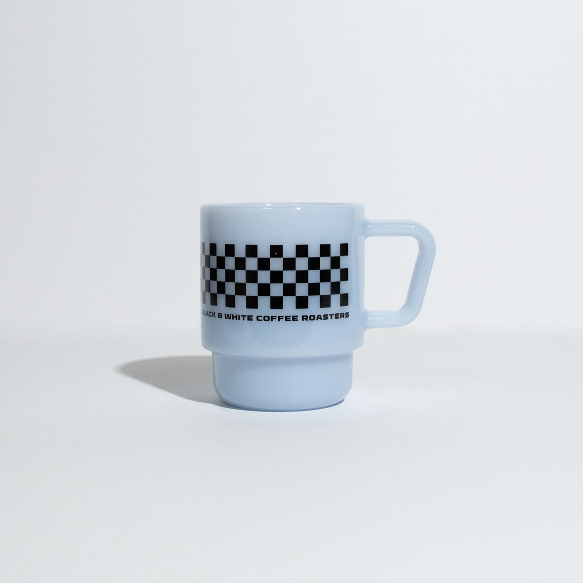 A light blue ceramic coffee mug with a black and white checkered band around the middle and the text 'BLACK & WHITE COFFEE ROASTERS' printed below it, set against a plain white background.